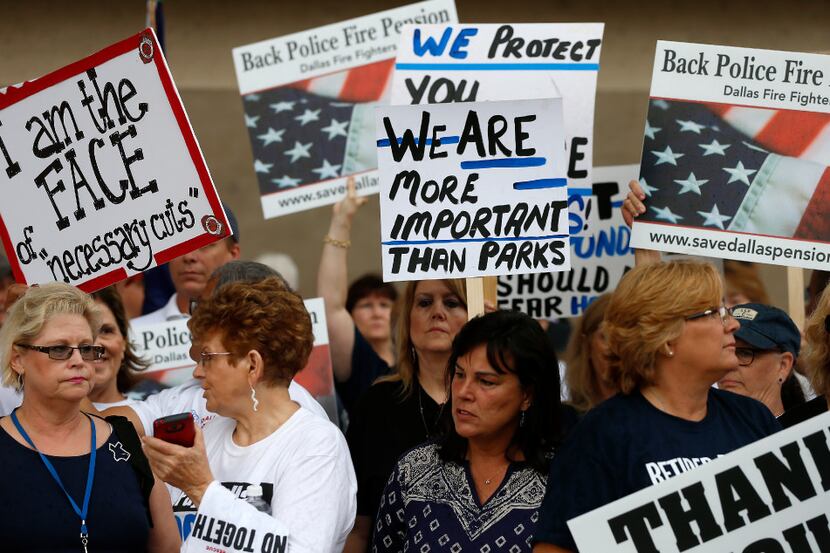 Dallas police and fire retirees gather holding pickets during a rally against Mayor Mike...