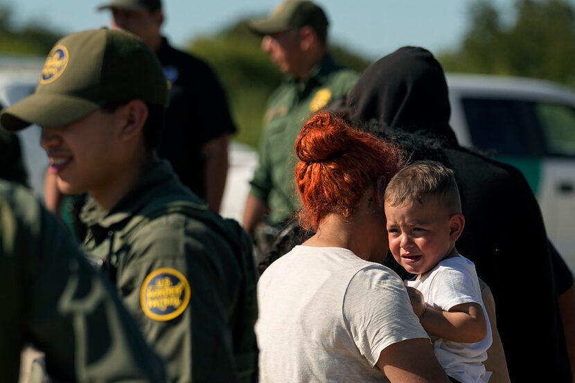 Migrants wait to be processed by the U.S. Customs and Border Patrol after they crossed the...