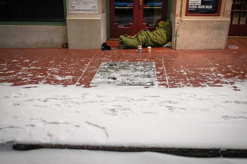 With temperatures in the single digits, a homeless person sleeps in the doorway of Dallas'...