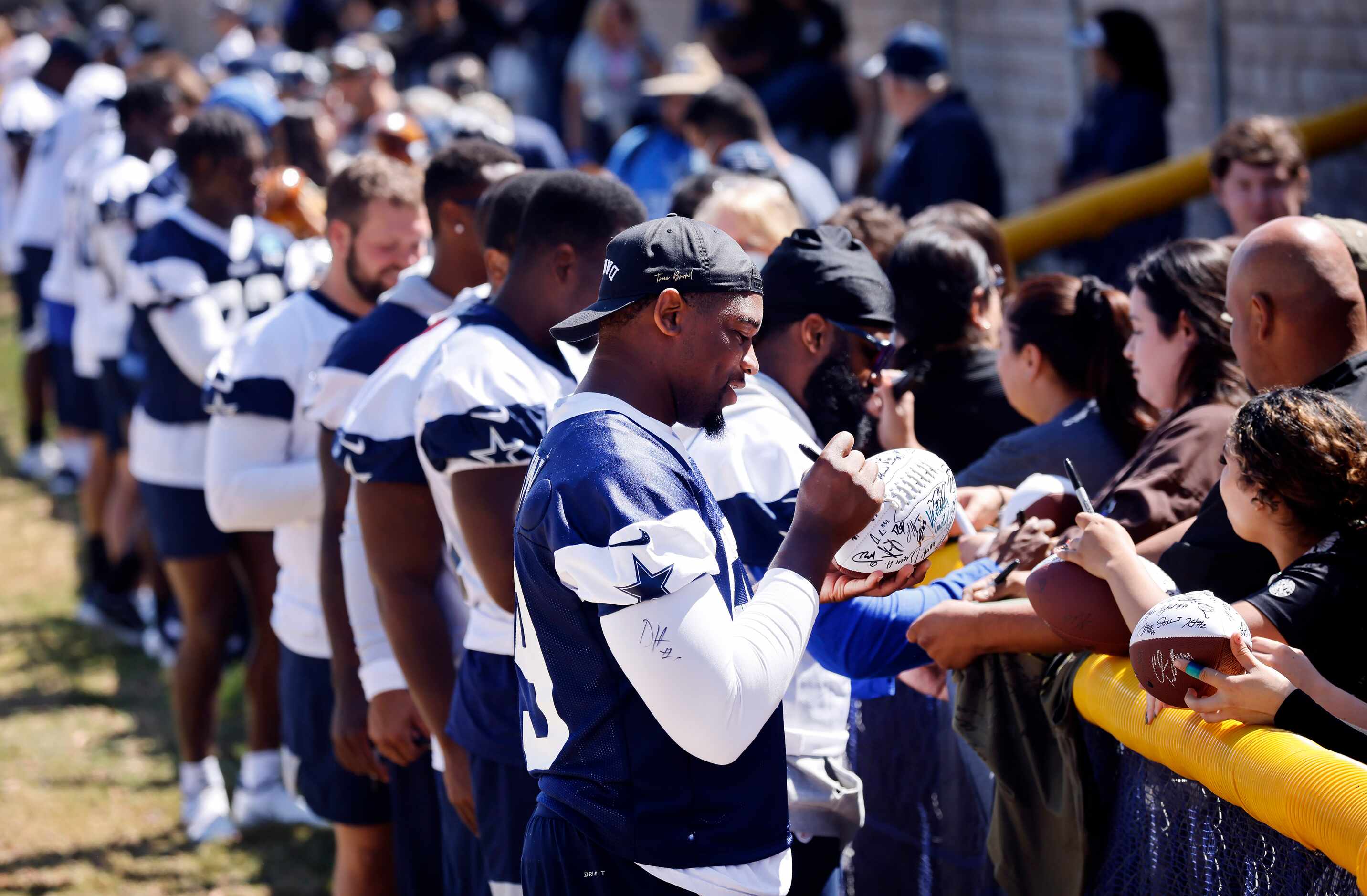 Dallas Cowboys defensive end Chauncey Golston (99) and his teammates sign autographs for...