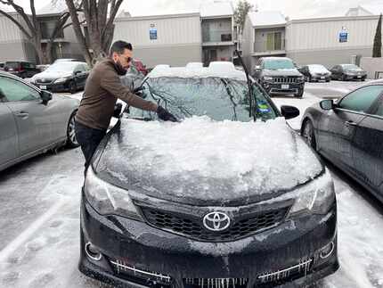 Víctor Jasson removes the ice from his car to drive to his shift at FedEx on Wednesday,...
