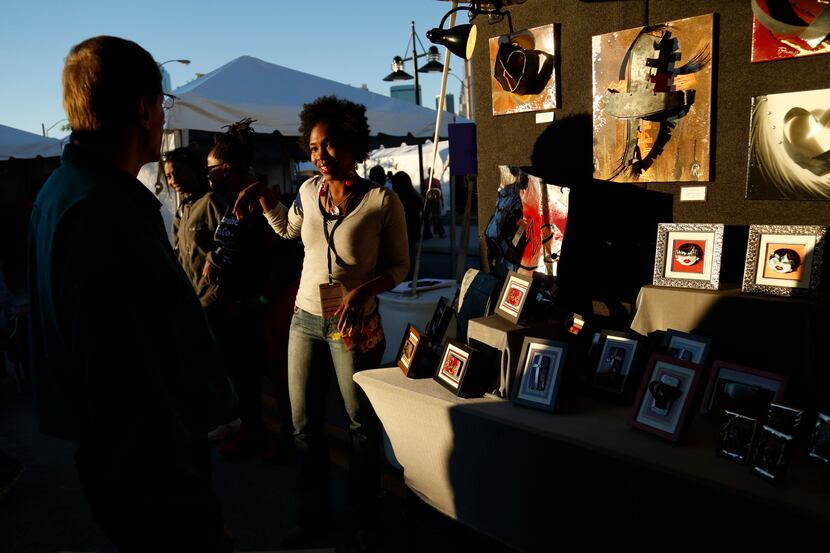 Artist Tyra Goodley, background center, talks with visitors at her booth during the Lamar...