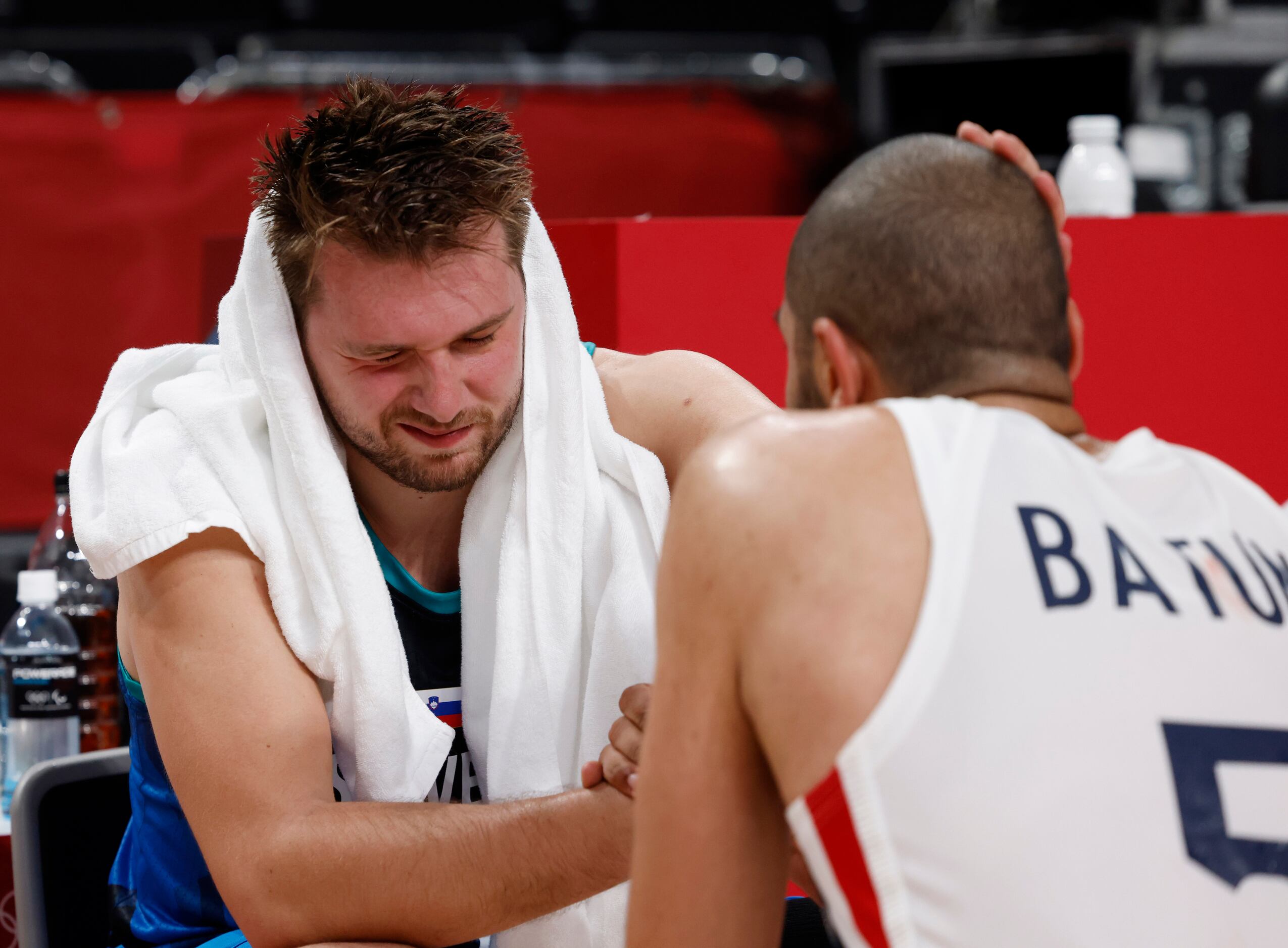 Slovenia’s Luka Doncic (77)  talks with France’s Nicolas Batum (5) as he sits dejected after...
