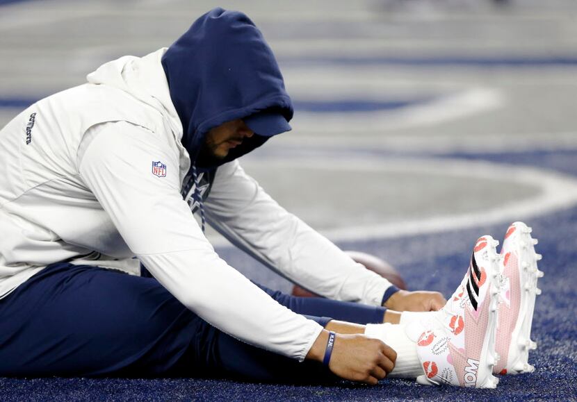 Dallas Cowboys quarterback Dak Prescott (4) stretches with a pair of shoes dedicated to his...