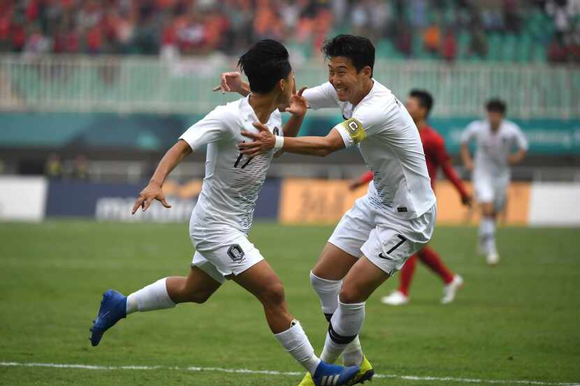 South Korea's Lee Seung-woo (L) celebrates with teammate Son Heung-min (R) after scoring...