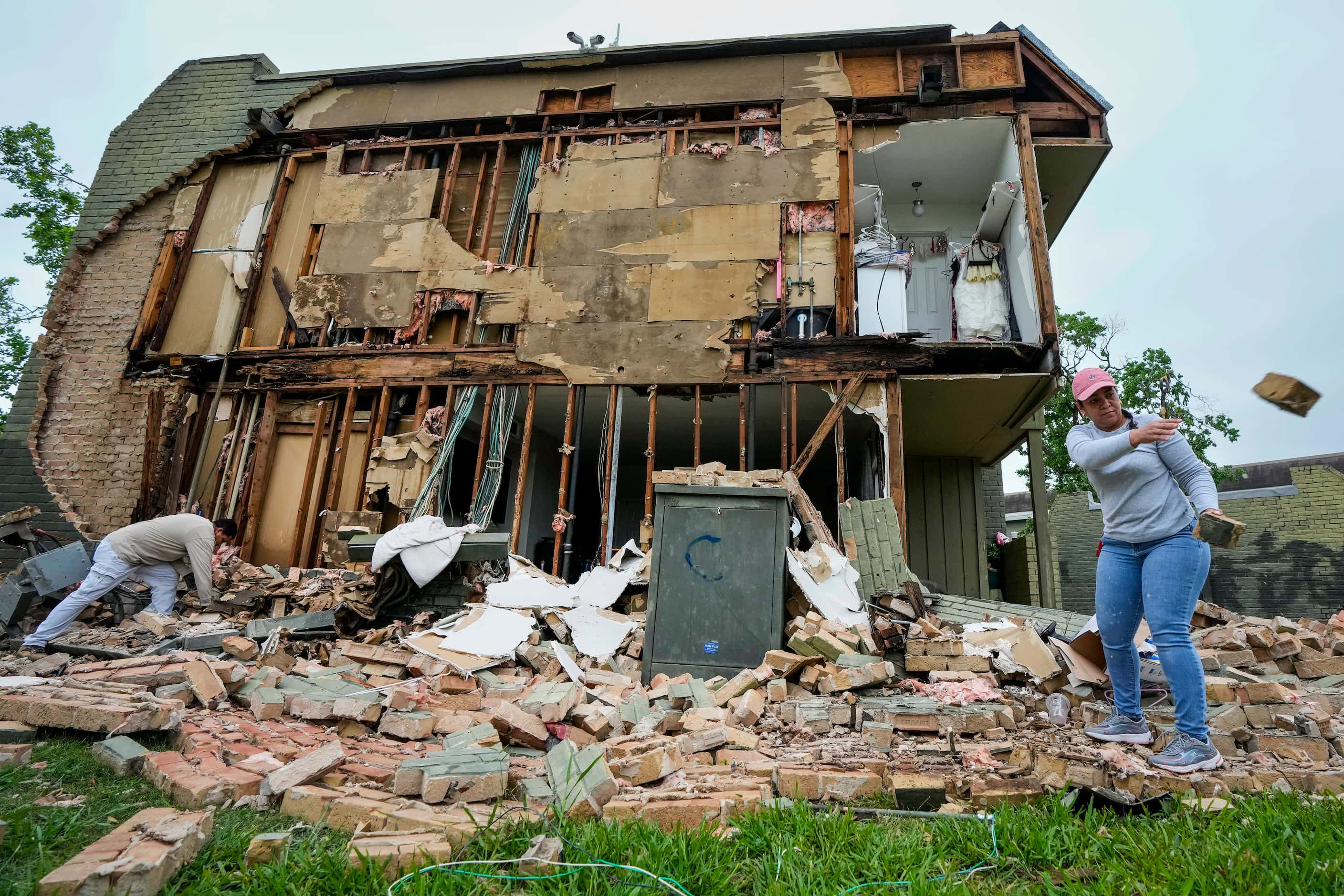 David Figueroa, left, and Delmy Suazo toss bricks to a pile as they work to clean up debris...