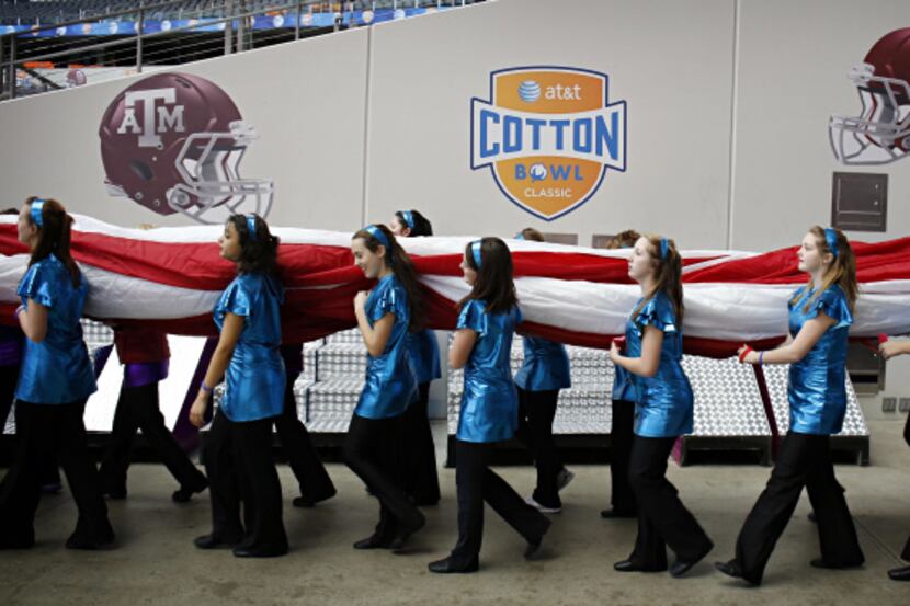 Dance team members carry a large American flag on to the field Thursday, during a dress...