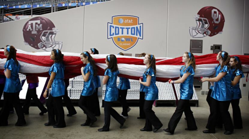 Dance team members carry a large American flag on to the field Thursday, during a dress...