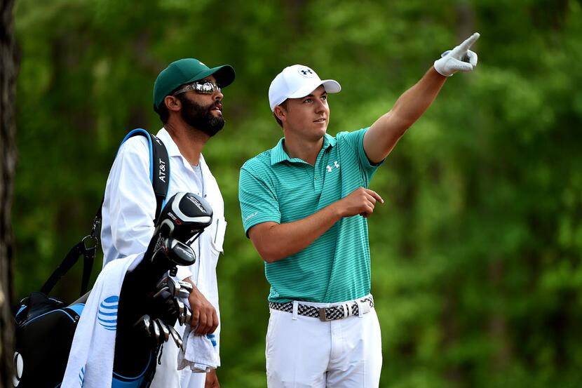 Jordan Spieth, right, explains his shot from the rough along the 11th fairway to his caddie,...