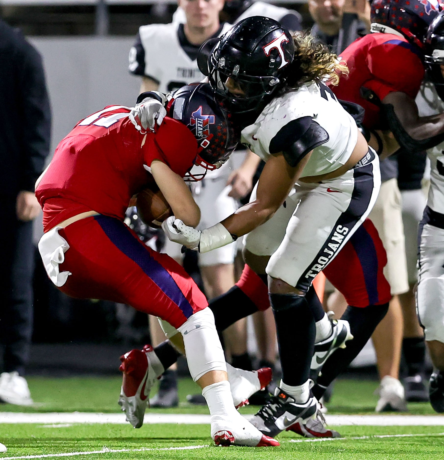 Justin Northwest quarterback Ryder Norton (11) is pulled down by Trinity linebacker Krystian...