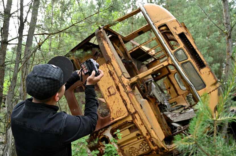 A visitor photographs the wreckage of a bus in the ghost city of Pripyat. The city was...