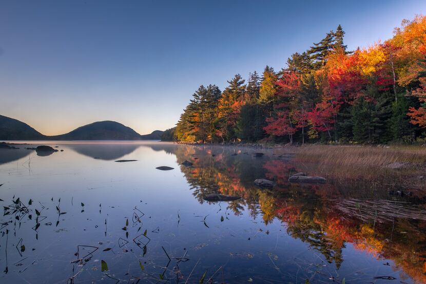 The fall colors reflect on the water along Eagle Lake Road in Acadia National Park. 