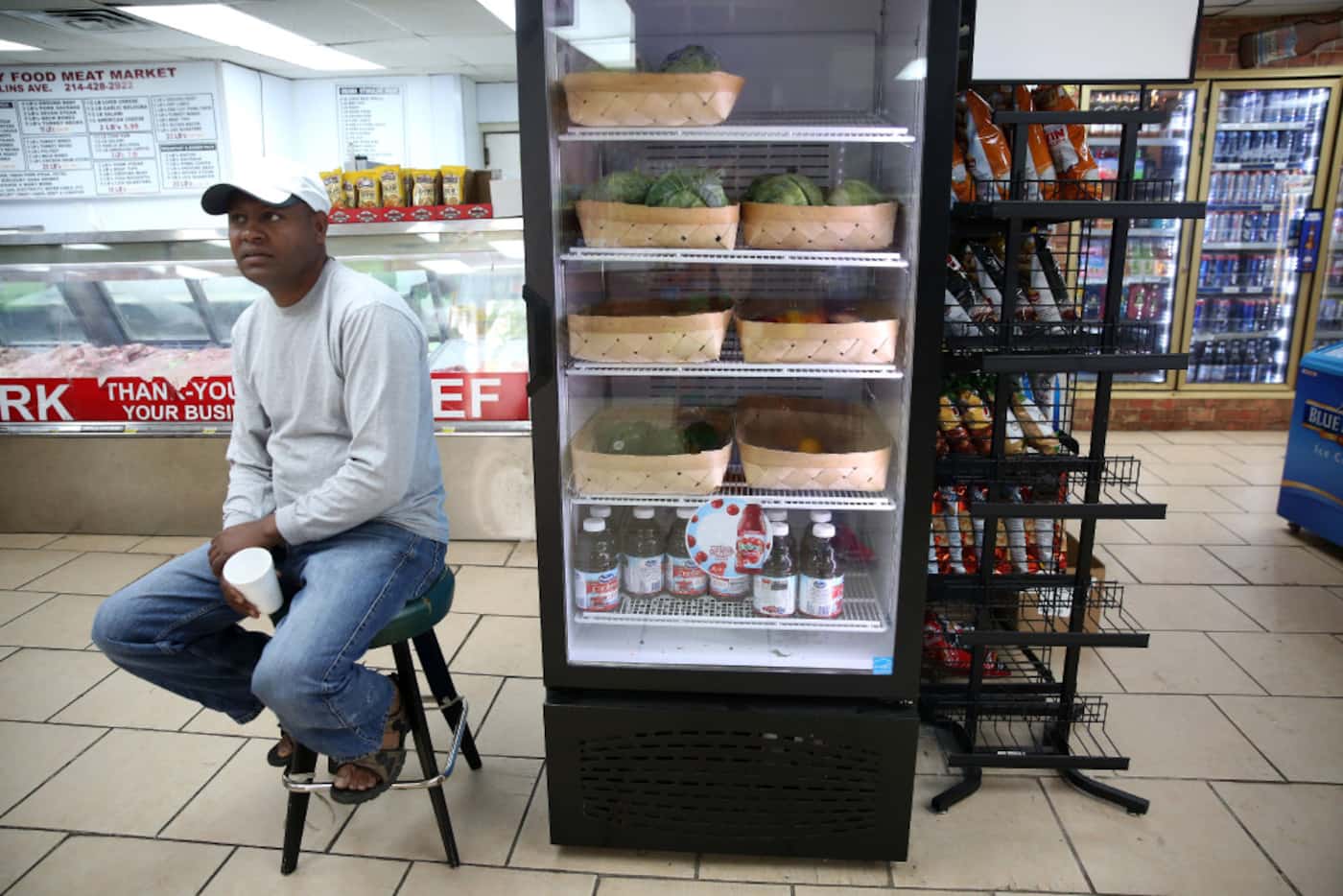 Owner Asnake Tarekegn talks to a customer next to the refrigerator at Hackney Food in the...