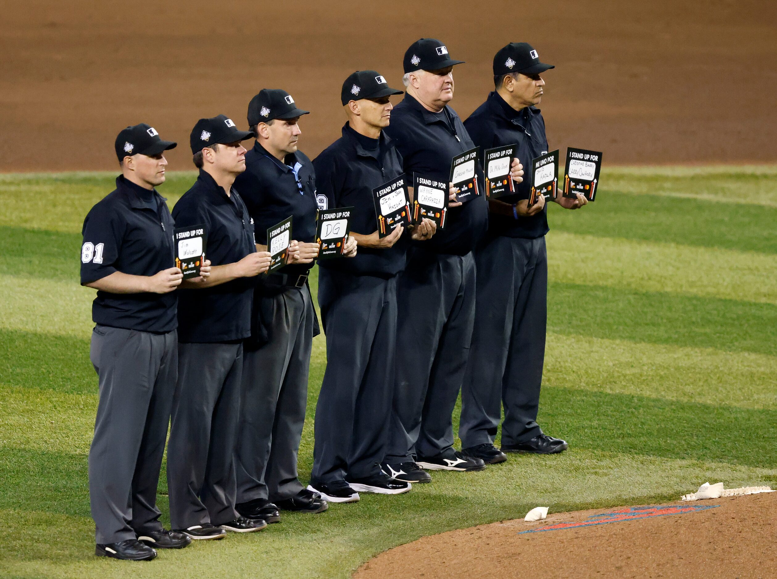 The umpires hold up Stand Up to Cancer signs after the fifth inning in Game 4 of the World...