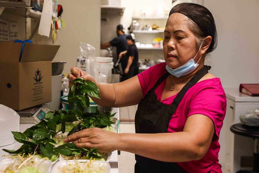 Ly Southammavong prepares some meals from the to-go menu that they offer at Ly Food Market...