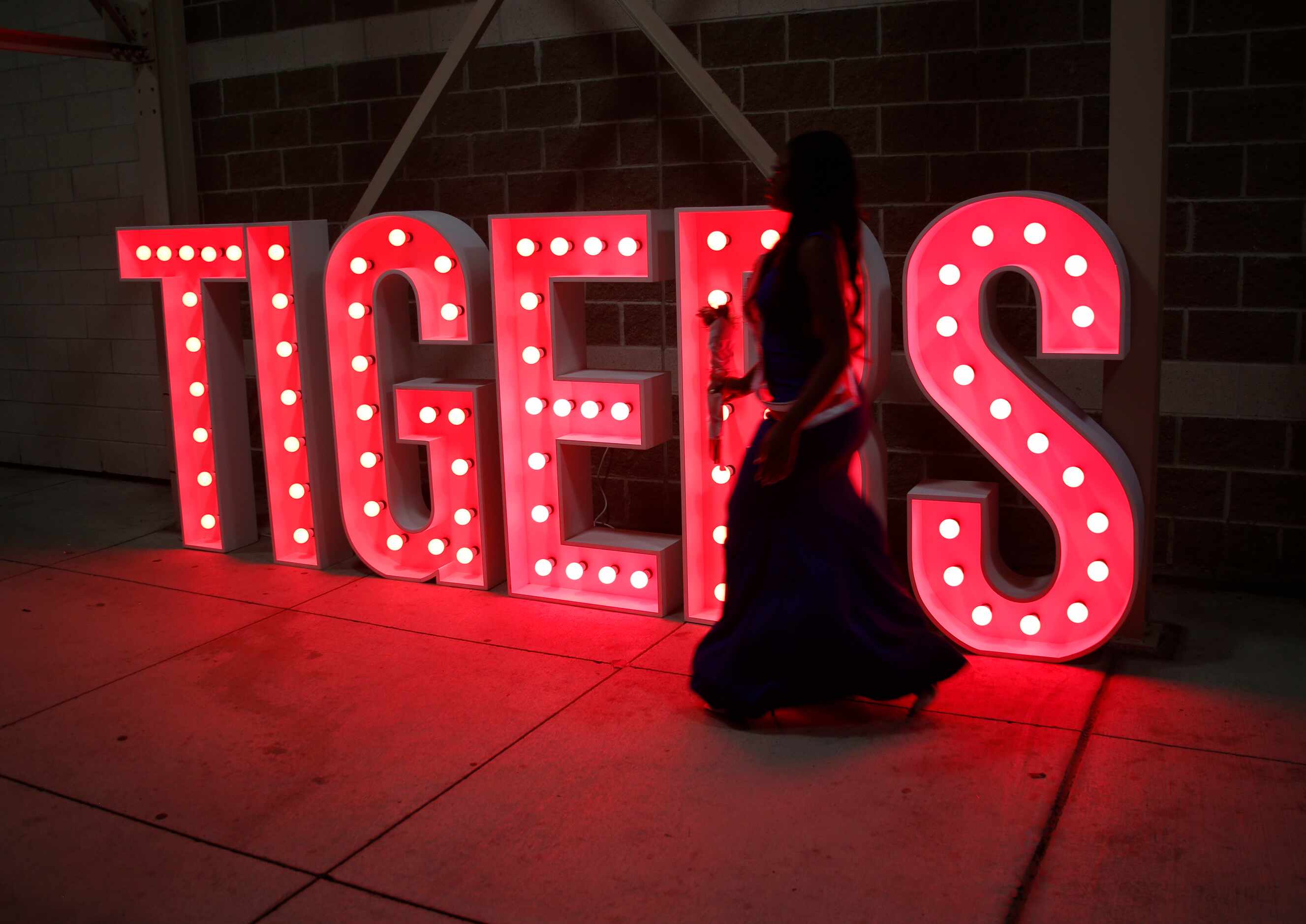 A member of the Tigers homecoming royalty passes alongside an illuminated sign near the...