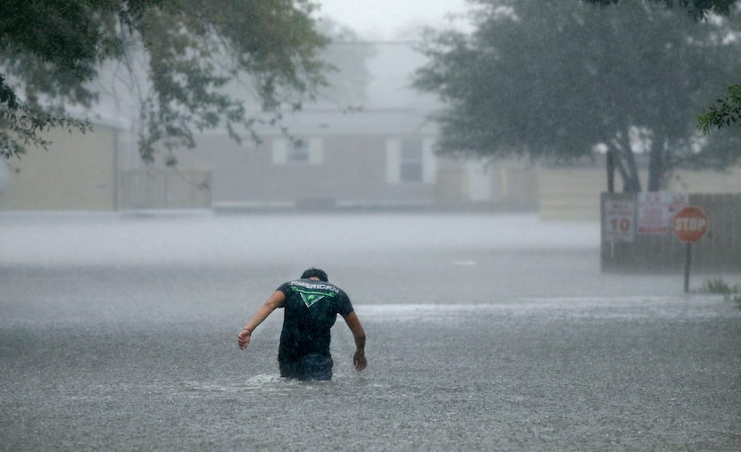 In a driving rainstorm, a man heads back into the flooded Pearland Acres mobile home...