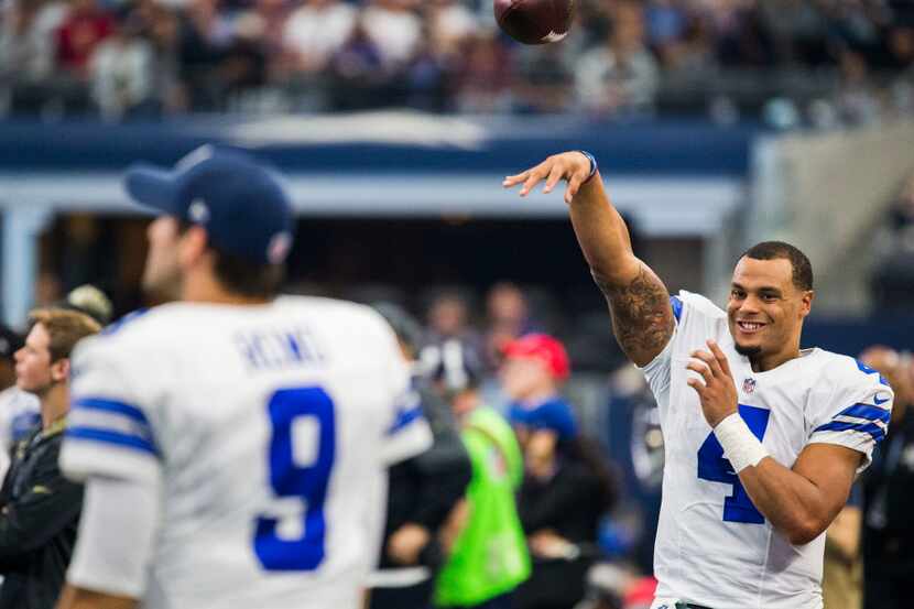 Dallas Cowboys quarterback Dak Prescott (4) warms up on the sideline with quarterback Tony...