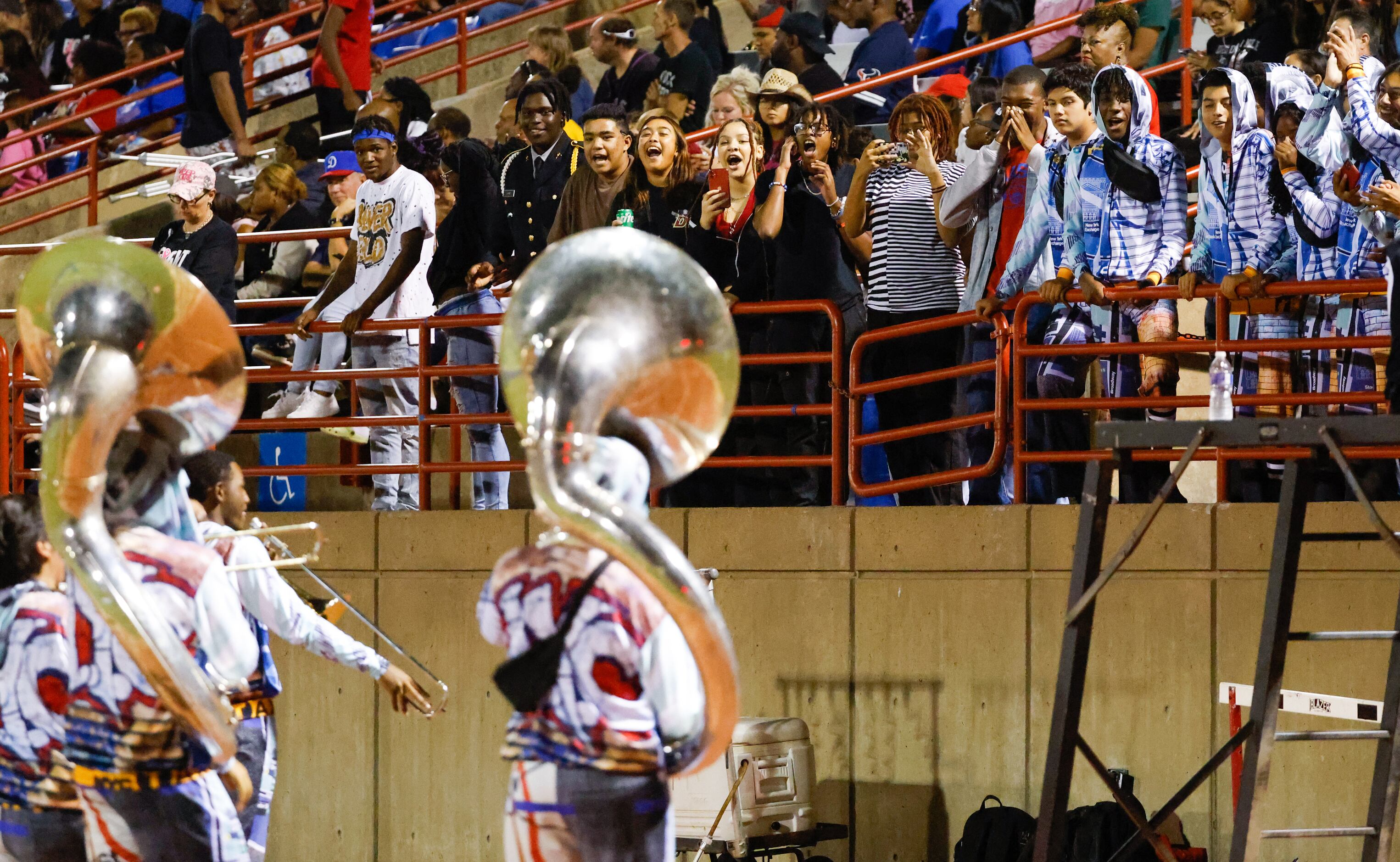 Duncanville band members and fans cheer for the brass players on the sidelines of a game...