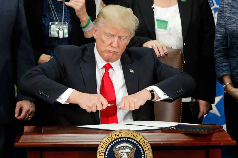 DAY 6 - President Donald Trump takes the cap off a pen before signing executive order for...
