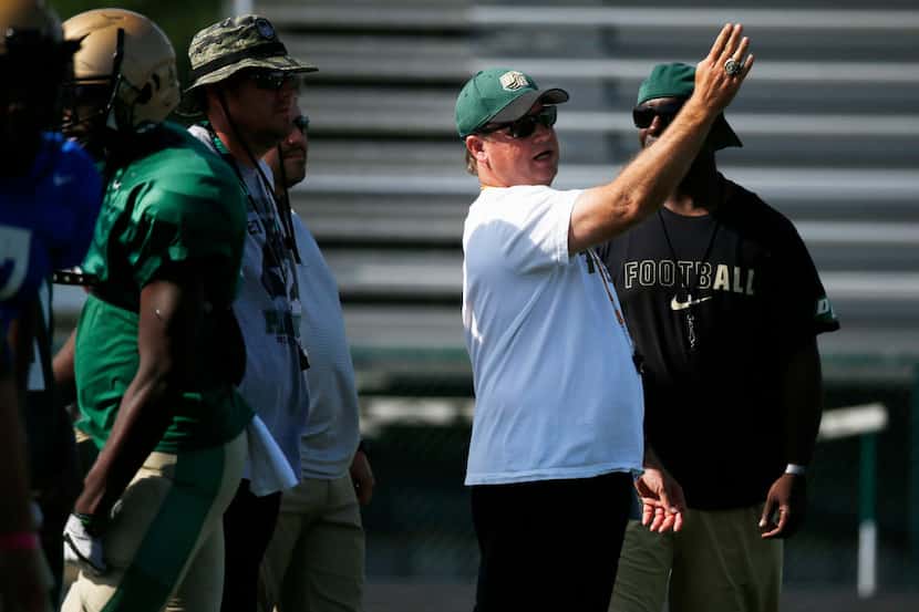 Todd Peterman (right) talks to the coaching staff at DeSoto during spring practice on April...