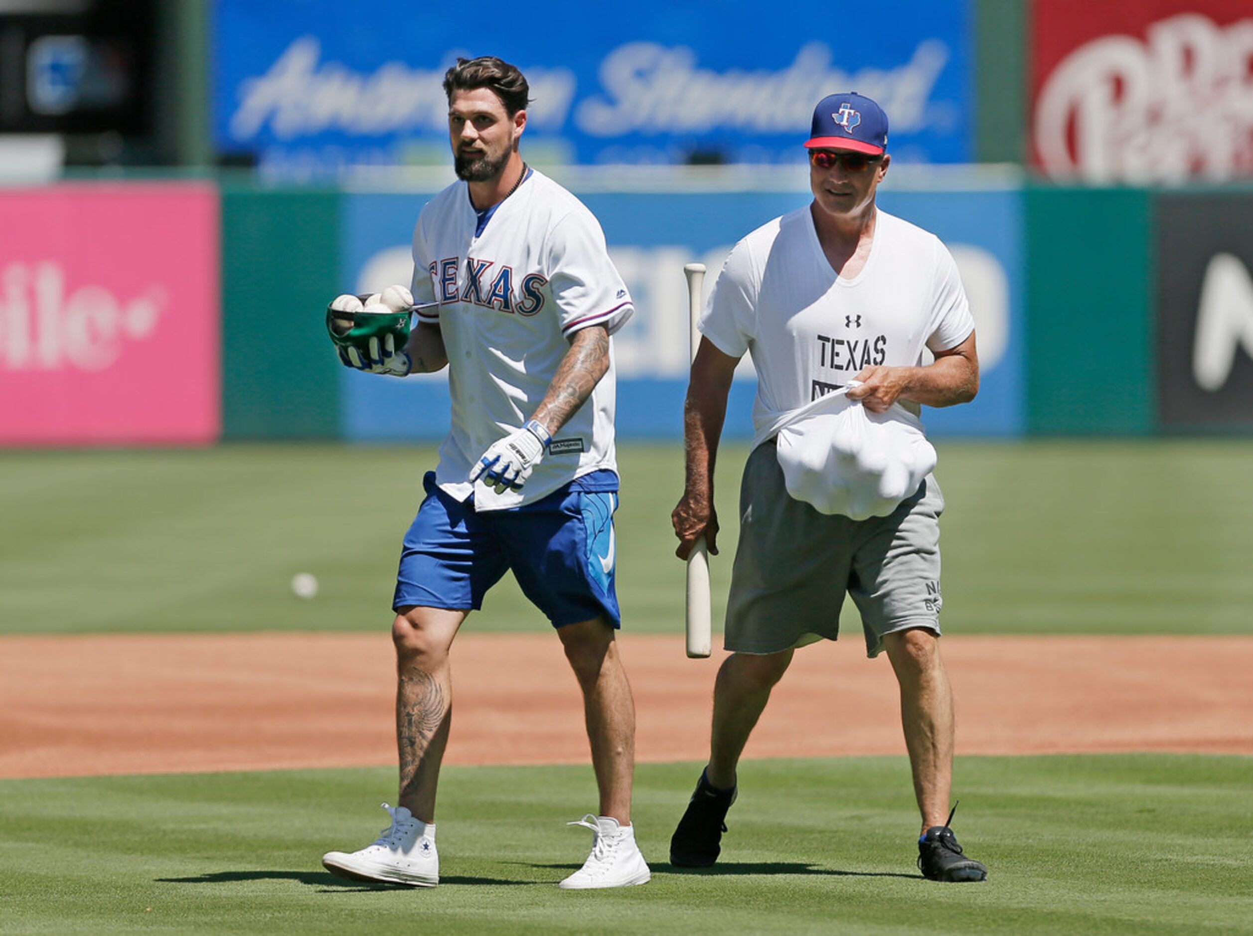 Dallas Stars captain Jamie Benn, left, uses his ball cap and Texas Rangers manager Jeff...