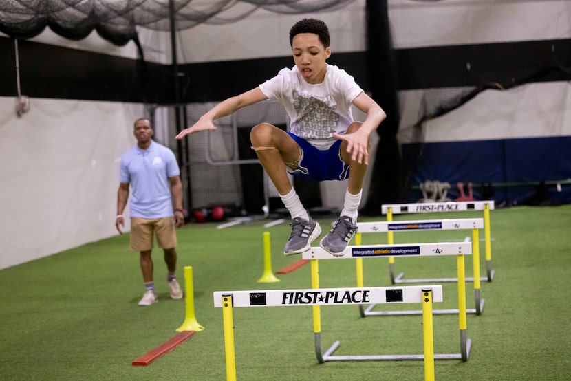 Performance specialist Marc Coleman watches as Mike Sorrell, 13, does power hurdle jumps...