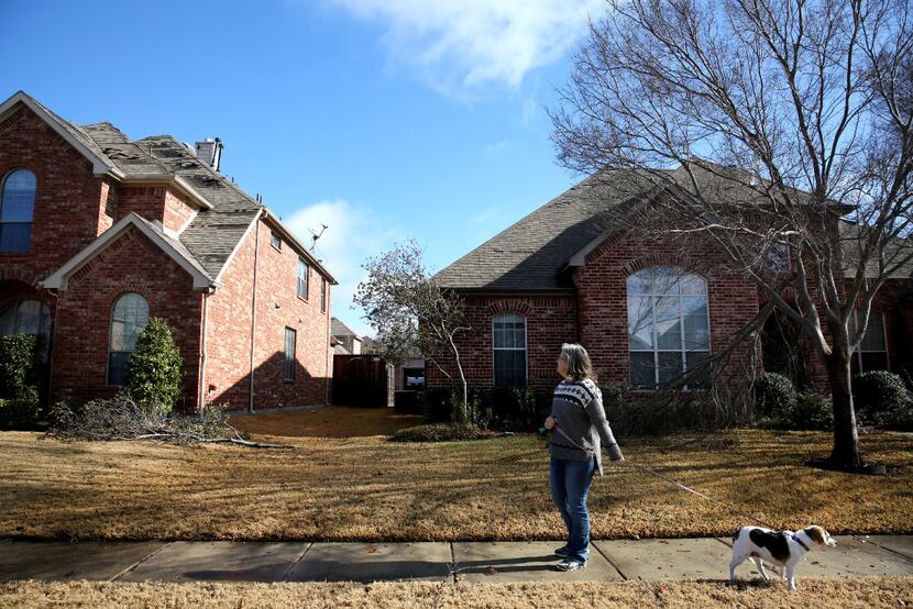 Sierra Theisen stops to look at a damaged home from a nighttime storm while walking her dog...