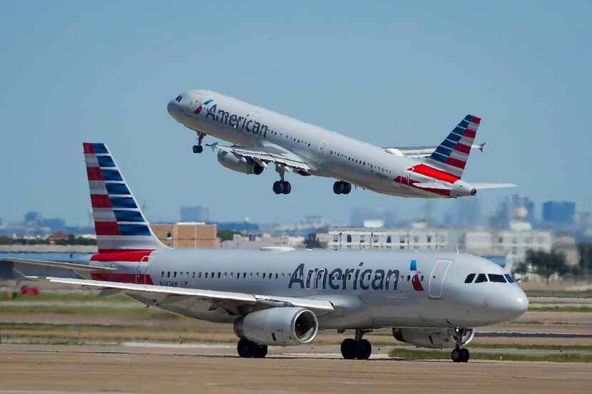 Un avión de American Airlines despega, mientras otro espera en la pista de la Terminal C en...
