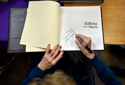 Bobbie Wygant, 92, signs a copy of her book "Talking to the Stars" to a fan after speaking...