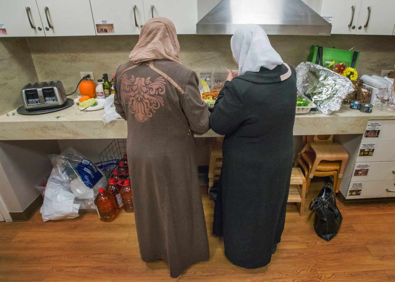 Syrian refugees and cooks Mariam Alshiblaq, left, and Maryam Alhow prepare tabbouleh at the...