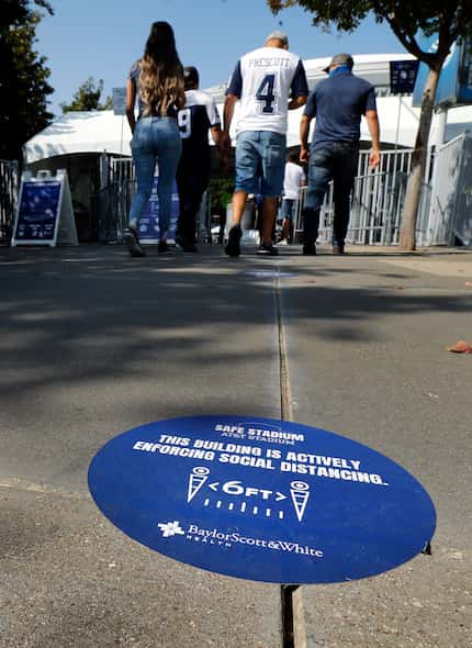 Markers on the ground reminds Dallas Cowboys fans to social distance as they arrive at AT&T...