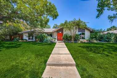 Front exterior of 1960s house with bright orange front door and white painted brick