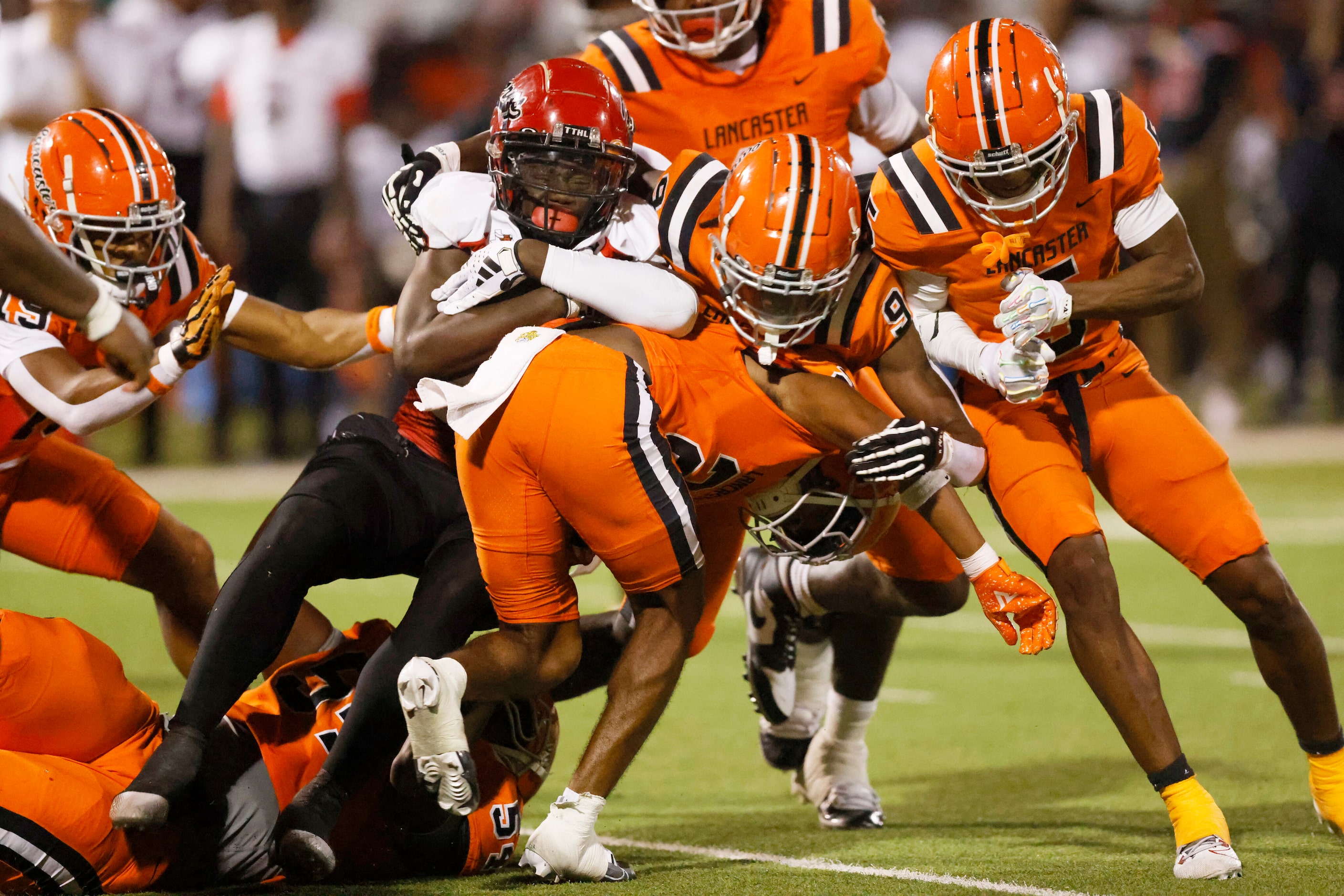 Cedar Hill running back Juelz Carter (22) is tackled by a handful of Lancaster players...