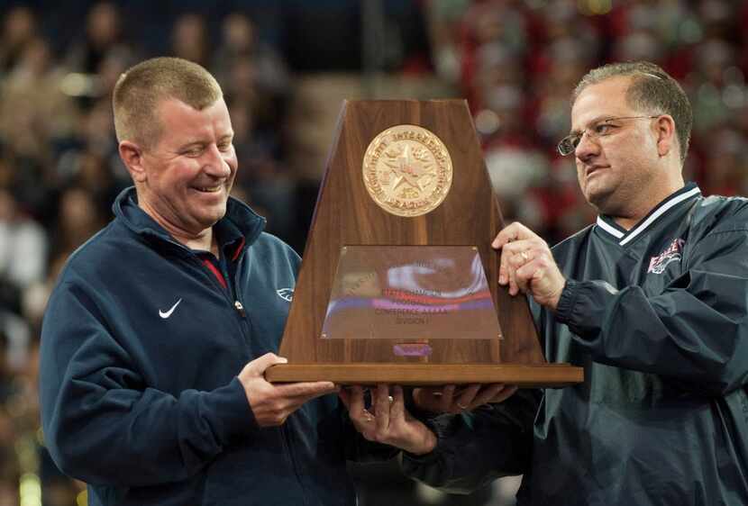 Head coach Tom Westerberg receives the UIL 5A state championship trophy from Allen ISD board...