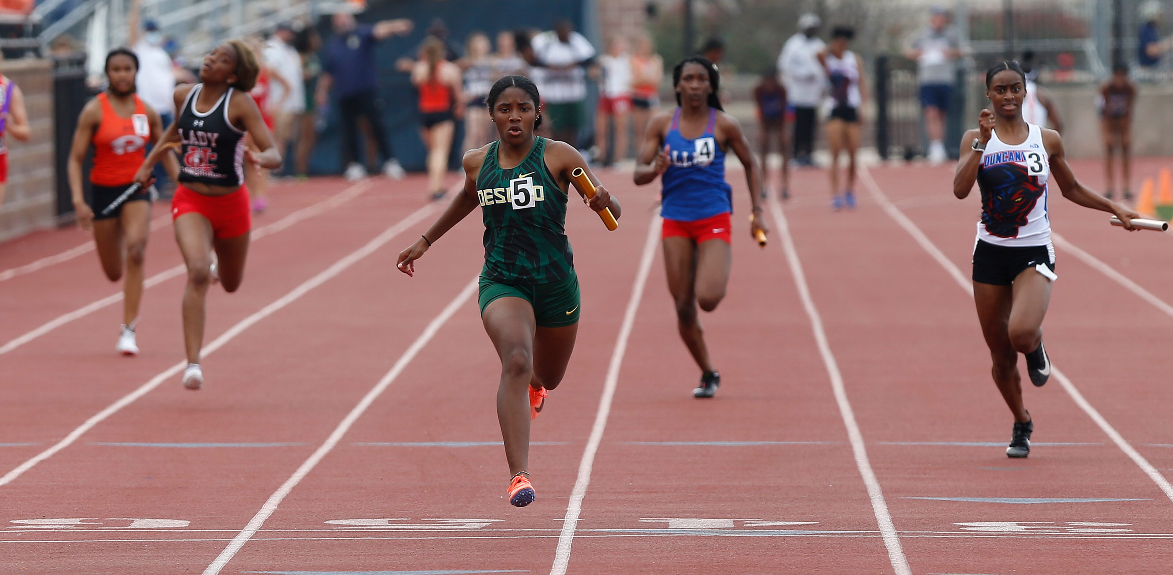 Mia Abraham (center) crosses the finish line first for DeSotto High School in the girls...