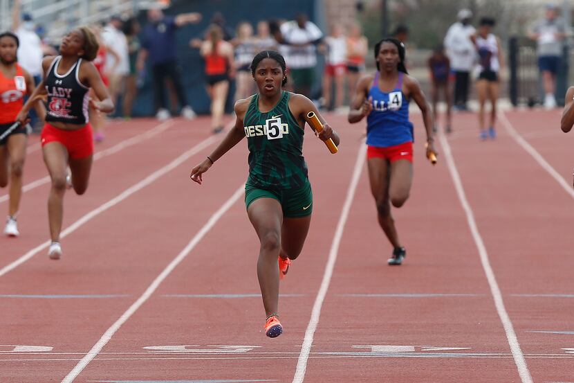 Mia Abraham (center) crosses the finish line first for DeSotto High School in the girls...