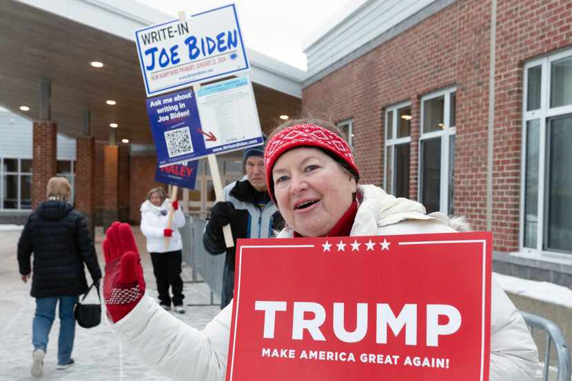 Tina Lorenz, derecha, y Ed Schoen, atrás, sostienen letreros de candidatos afuera de la...