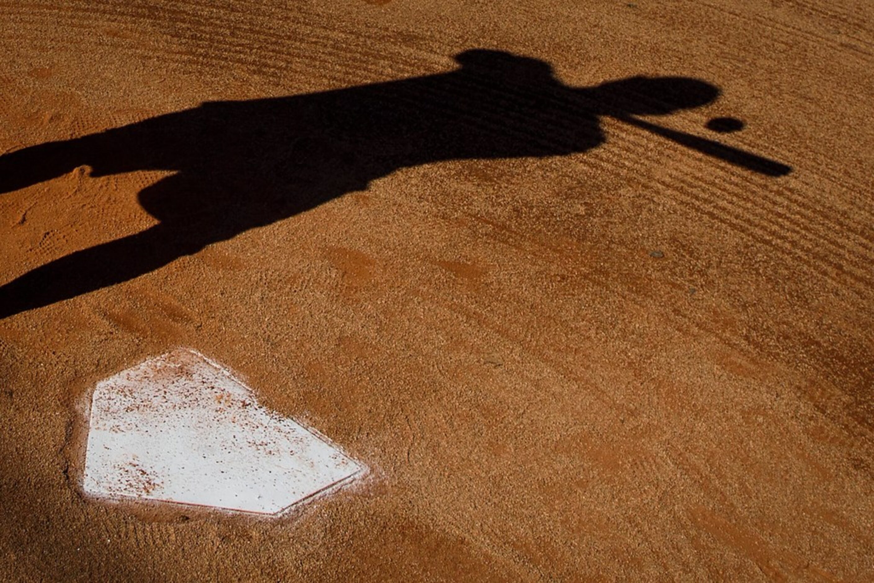 Texas Rangers infielder Asdrubal Cabrera casts a shadow as he hits grounders to his son...