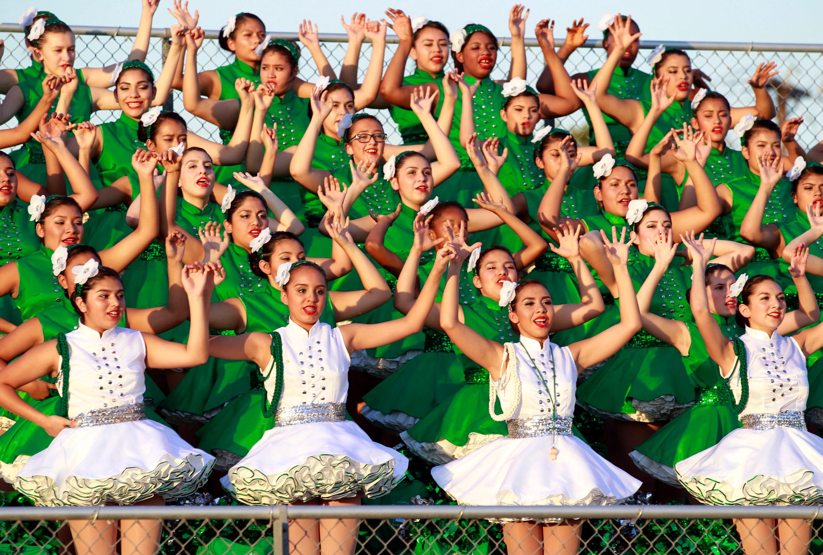 (TXHSFB) Bryan Adams High drill team members raise their hands during the school's song...