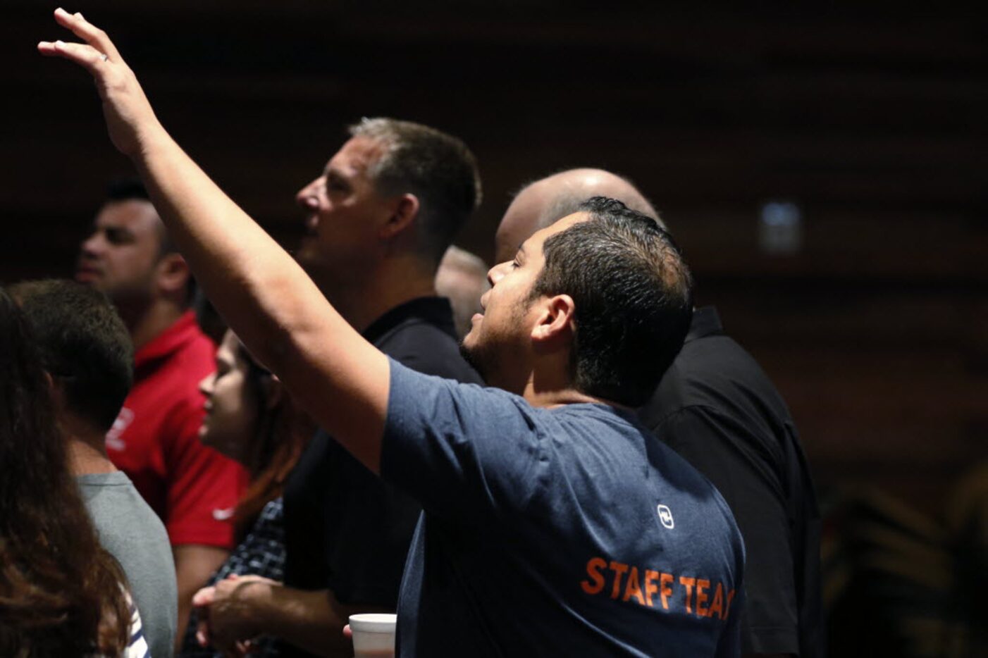 Oscar Castillo, right, and Todd Wagner, center, sing during the Tuesday Staff Prayer meeting.