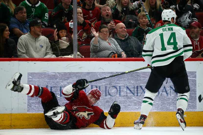 Dallas Stars left wing Jamie Benn (14) sends Arizona Coyotes left wing Lawson Crouse (67) to...