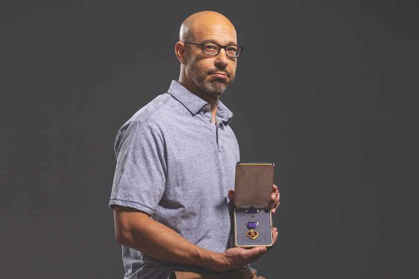 Angel Ayala holds his Purple Heart medal for a photo.