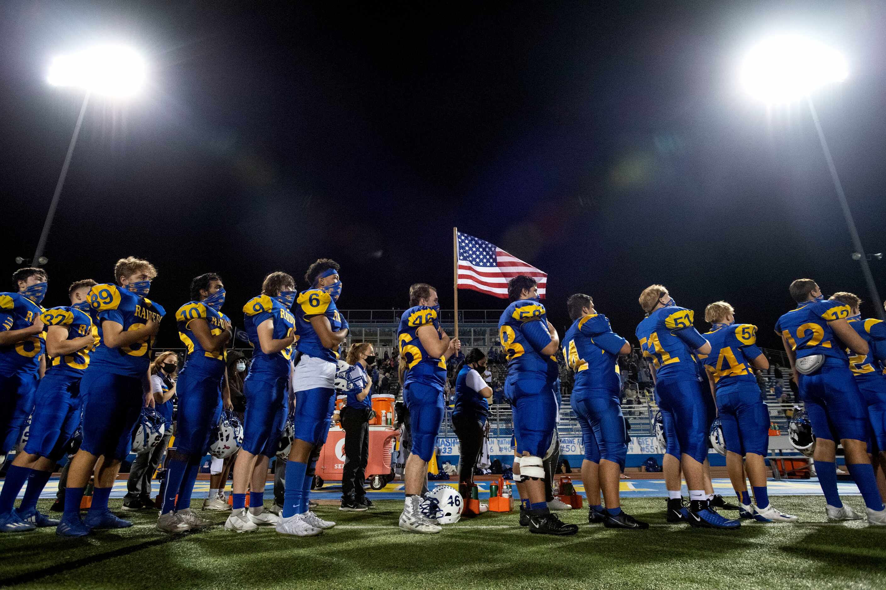 The Sunnyvale Raiders stand for the national anthem before a high school football game...