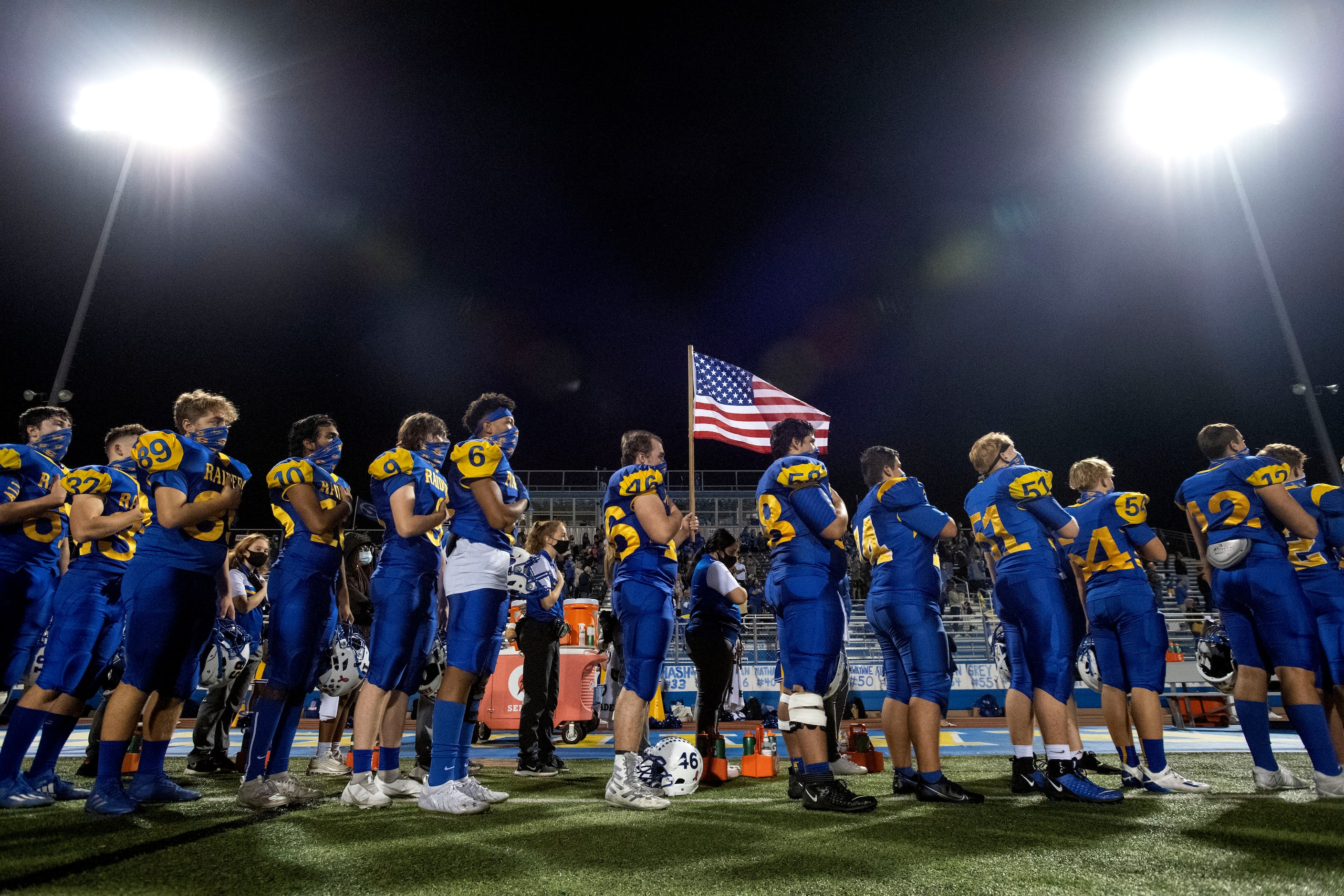 The Sunnyvale Raiders stand for the national anthem before a high school football game...