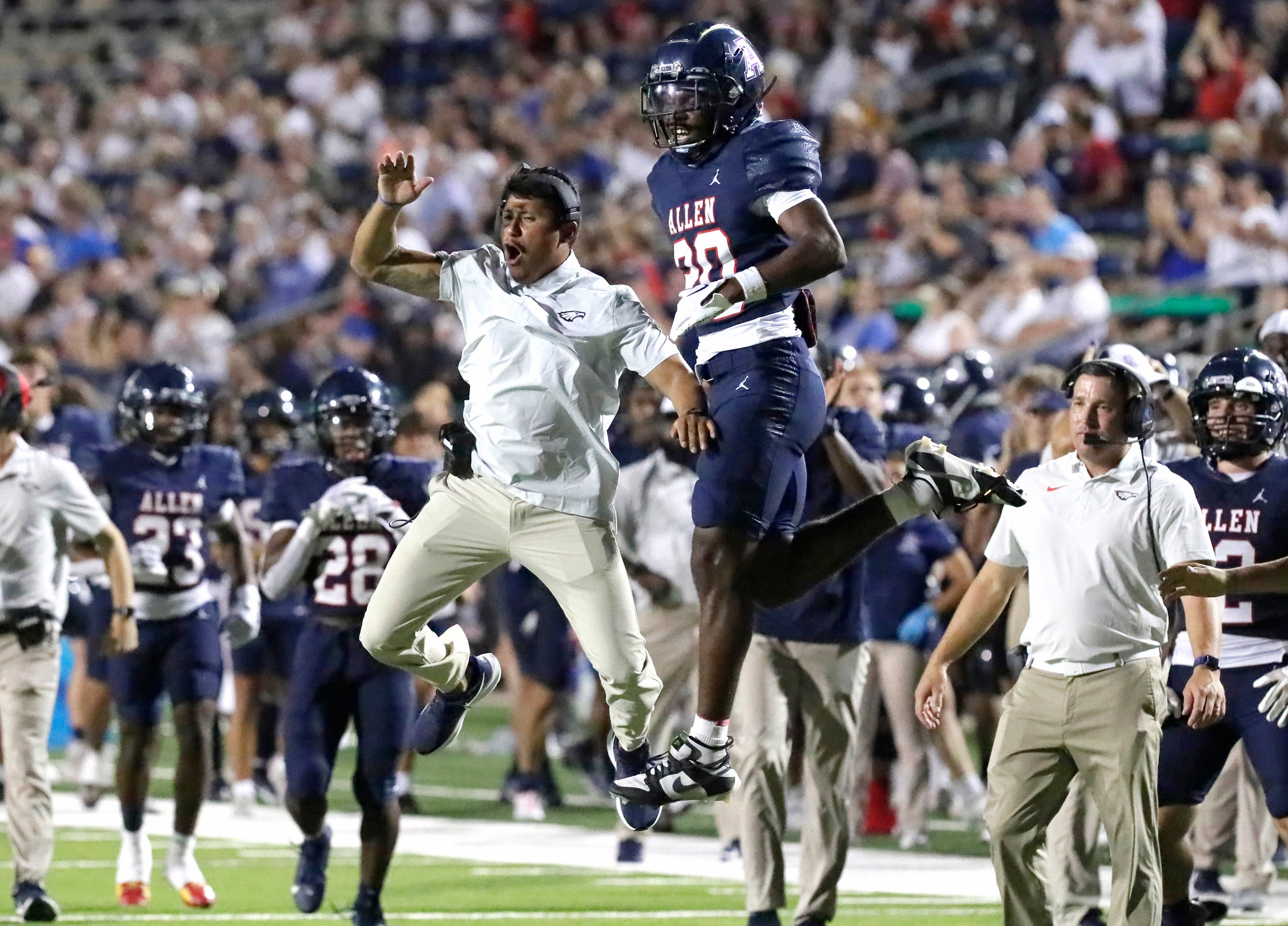 Allen High School assistant coach Victor Gonzales leaps with Allen High School defensive...