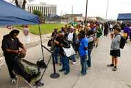 People wait on line as barber King Jaymes Bell (left) gives haircut to an individual during...
