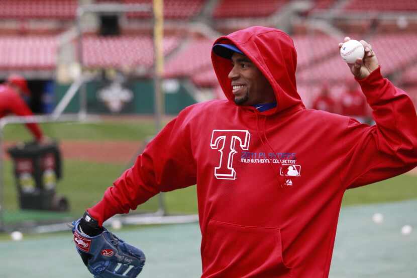Texas Rangers player Endy Chavez, tries to stay warm while  throwing during practice, prior...