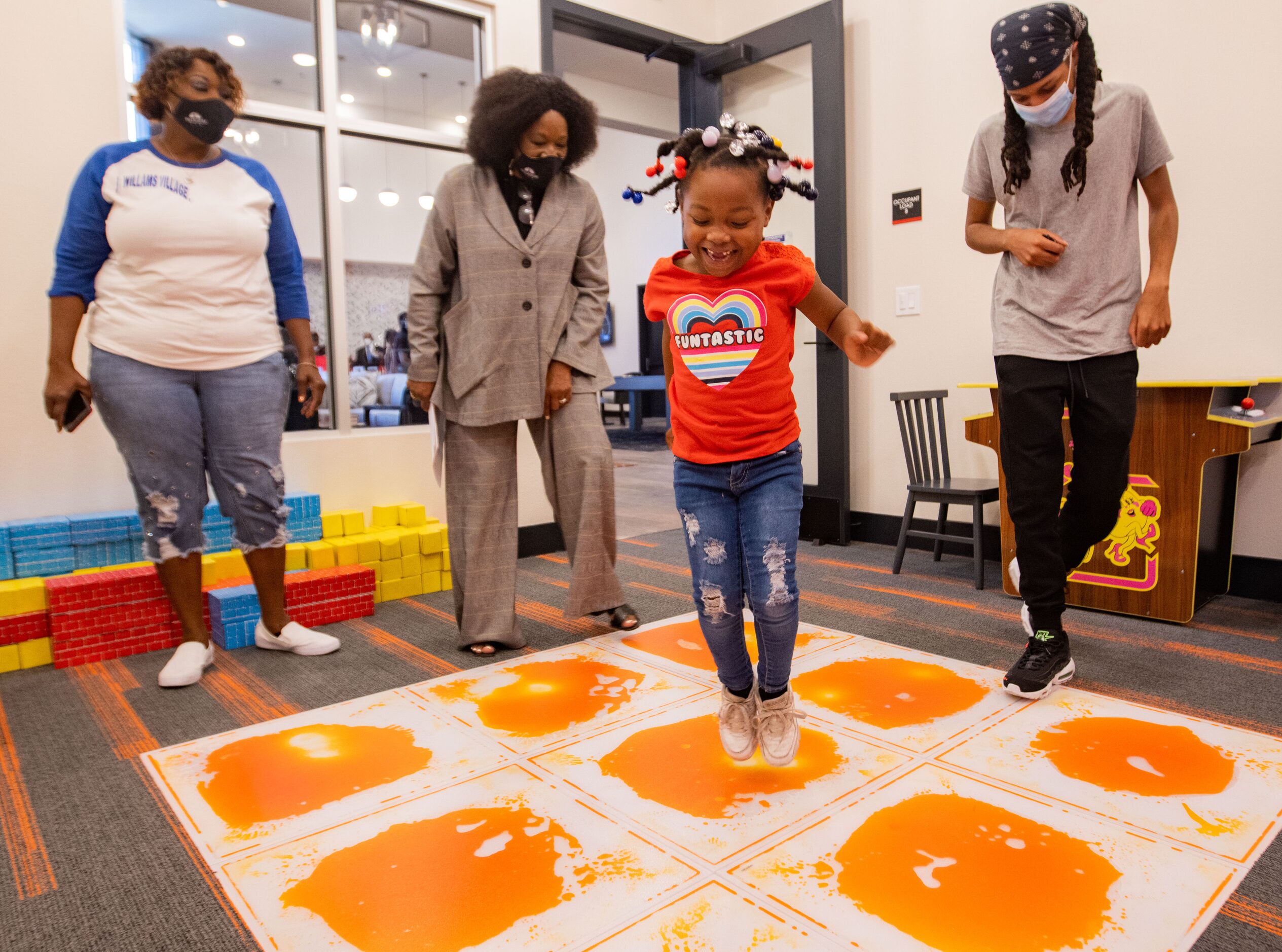 Jazmine Williams, 5, jumps in the playroom while Palladium regional manager April West...