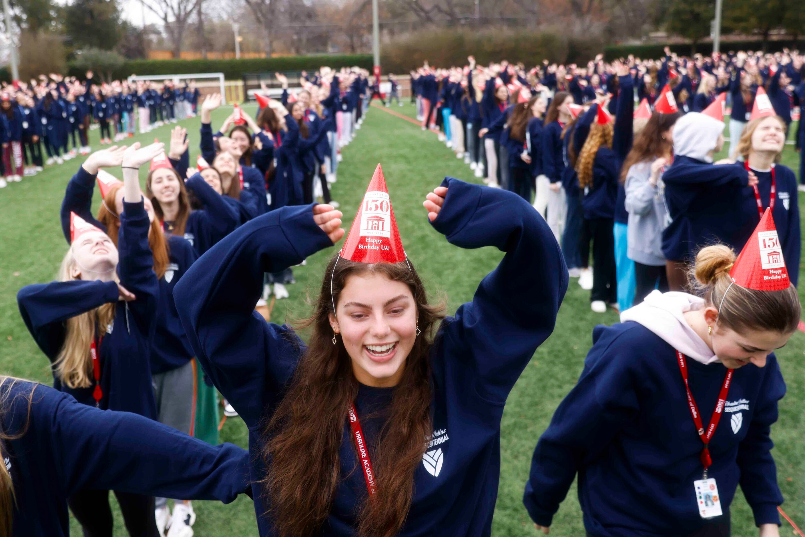 Student Eloise Love (center) cheer while standing for a formation of "UA 150" for a giant...